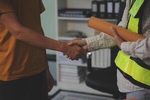 Architect men making handshake in construction site. Employee or worker shake hands to employer man for greeting, dealing, teamwork, collaboration some project or business. They are good team photo