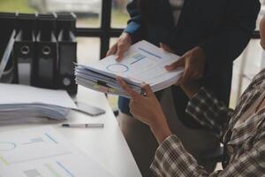 Group of confident business people point to graphs and charts to analyze market data, balance sheet, account, net profit to plan new sales strategies to increase production capacity. photo