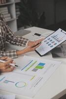 Group of confident business people point to graphs and charts to analyze market data, balance sheet, account, net profit to plan new sales strategies to increase production capacity. photo