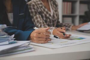 Group of confident business people point to graphs and charts to analyze market data, balance sheet, account, net profit to plan new sales strategies to increase production capacity. photo