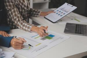 Group of confident business people point to graphs and charts to analyze market data, balance sheet, account, net profit to plan new sales strategies to increase production capacity. photo