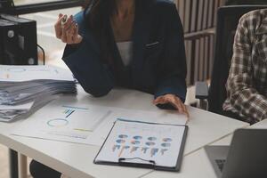 Group of confident business people point to graphs and charts to analyze market data, balance sheet, account, net profit to plan new sales strategies to increase production capacity. photo