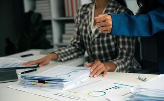Group of confident business people point to graphs and charts to analyze market data, balance sheet, account, net profit to plan new sales strategies to increase production capacity. photo