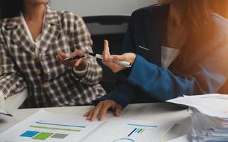Group of confident business people point to graphs and charts to analyze market data, balance sheet, account, net profit to plan new sales strategies to increase production capacity. photo