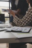 Group of confident business people point to graphs and charts to analyze market data, balance sheet, account, net profit to plan new sales strategies to increase production capacity. photo