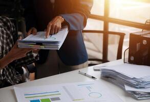 Group of confident business people point to graphs and charts to analyze market data, balance sheet, account, net profit to plan new sales strategies to increase production capacity. photo