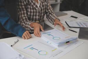 Group of confident business people point to graphs and charts to analyze market data, balance sheet, account, net profit to plan new sales strategies to increase production capacity. photo
