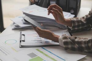 Group of confident business people point to graphs and charts to analyze market data, balance sheet, account, net profit to plan new sales strategies to increase production capacity. photo