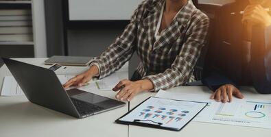 Group of confident business people point to graphs and charts to analyze market data, balance sheet, account, net profit to plan new sales strategies to increase production capacity. photo