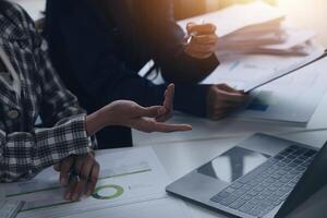 Group of confident business people point to graphs and charts to analyze market data, balance sheet, account, net profit to plan new sales strategies to increase production capacity. photo