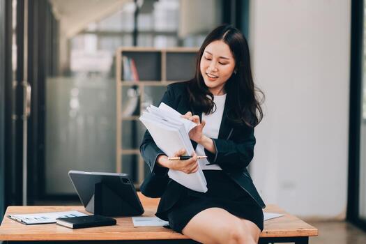 Asian businesswoman talking on phone, using laptop, looking at screen, entrepreneur manager consulting client by call, looking at computer screen, discussing project, reading information photo