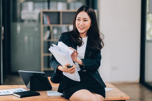 Asian businesswoman talking on phone, using laptop, looking at screen, entrepreneur manager consulting client by call, looking at computer screen, discussing project, reading information photo