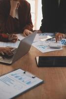 Group of confident business people point to graphs and charts to analyze market data, balance sheet, account, net profit to plan new sales strategies to increase production capacity. photo
