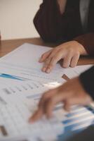 Group of confident business people point to graphs and charts to analyze market data, balance sheet, account, net profit to plan new sales strategies to increase production capacity. photo