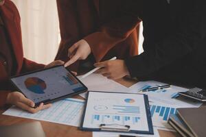 Group of confident business people point to graphs and charts to analyze market data, balance sheet, account, net profit to plan new sales strategies to increase production capacity. photo