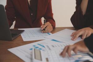 Group of confident business people point to graphs and charts to analyze market data, balance sheet, account, net profit to plan new sales strategies to increase production capacity. photo