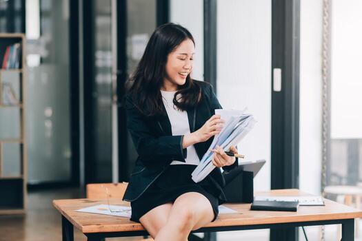 Asian businesswoman talking on phone, using laptop, looking at screen, entrepreneur manager consulting client by call, looking at computer screen, discussing project, reading information photo
