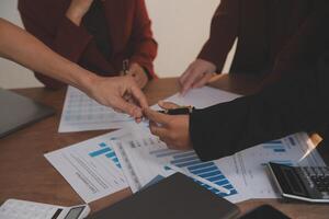 Group of confident business people point to graphs and charts to analyze market data, balance sheet, account, net profit to plan new sales strategies to increase production capacity. photo