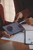Group of confident business people point to graphs and charts to analyze market data, balance sheet, account, net profit to plan new sales strategies to increase production capacity. photo