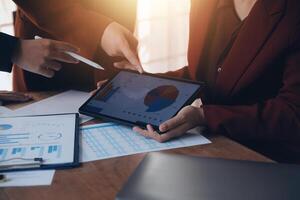 Group of confident business people point to graphs and charts to analyze market data, balance sheet, account, net profit to plan new sales strategies to increase production capacity. photo