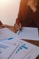 Group of confident business people point to graphs and charts to analyze market data, balance sheet, account, net profit to plan new sales strategies to increase production capacity. photo