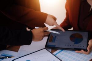 Group of confident business people point to graphs and charts to analyze market data, balance sheet, account, net profit to plan new sales strategies to increase production capacity. photo