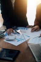 Group of confident business people point to graphs and charts to analyze market data, balance sheet, account, net profit to plan new sales strategies to increase production capacity. photo