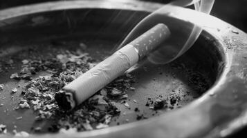 Black and white photo of burning cigarette in ashtray
