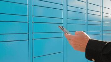 Automated parcel locker. Person receives a parcel from a courier service by opening a mailbox through an application on his phone video