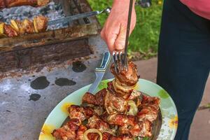 Cooked kebabs on the grill with smoke. Fresh brown BBQ meat cooked on an outdoor grill photo