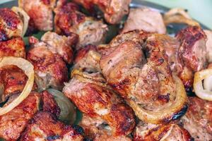 Cooked kebabs on the grill with smoke. Fresh brown BBQ meat cooked on an outdoor grill photo