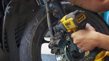 Mechanic using a impact wrench and socket on a motorcycle in garage, video