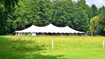 Large white tent at the edge of the forest photo