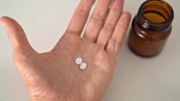 Woman Holding Several of Pills in Her Palm, Slowly Unfolding Fingers, Brown Bottle is on Table, Close-Up of Hand and Tablets, Medicine and Health Concept video