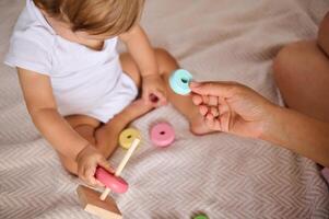 Close-up of a baby playing with colorful stacking toy with parent's assistance photo