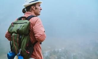 Man with backpack exploring foggy mountain landscape, embracing adventure in nature photo