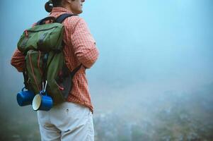 Solo hiker in outdoor gear exploring a misty mountain trail with backpack and camping essentials photo