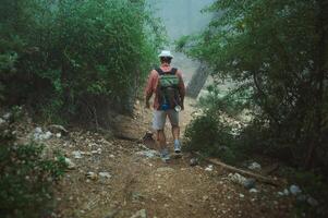 Man hiking on a foggy forest trail with a backpack in wilderness photo