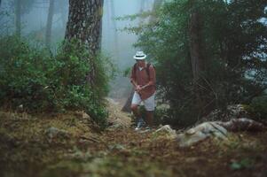 Man hiking in foggy forest wearing hat and backpack, enjoying nature and adventure photo