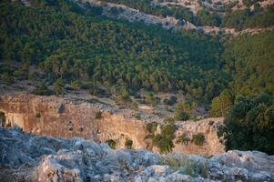 Scenic view of forested mountain landscape with cliff edge and dense trees at sunrise photo