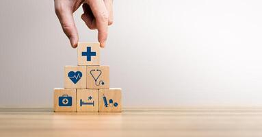 Health insurance concept, Hand Arranging Wooden Blocks with Medical Icons Including Heartbeat, Stethoscope, Syringe, and Healthcare Cross Symbol, Future Healthcare Technology photo