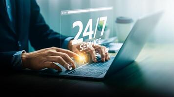 Businessman Providing 24 7 Online Support Service Through Laptop with Digital Interface Hologram Displaying Various Customer Assistance Icons, Representing Constant Availability photo
