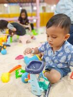 a toddler boy is playing with sand on the playground photo