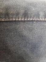 the stitching and texture of the old grayish black jeans photo