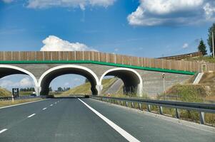 Modern highway with an overpass bridge on a sunny day with blue skies and white clouds photo