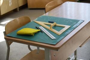 Classroom desk with math tools, ruler, and eraser on a cutting mat photo