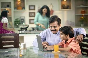 Father Helping Son By Studying Online Using A Laptop photo