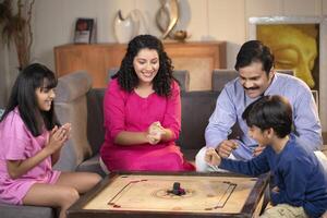Charming Family Playing Carrom Board Game Together At Home photo