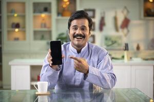 Cheerful Man Looking At Camera Pointing Finger At Empty Phone Screen photo