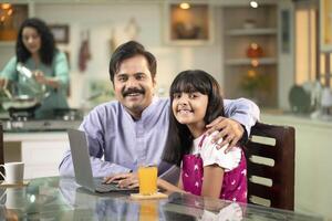 Handsome Daddy And Daughter Sitting At Dining Table While Posing In Front Of Camera photo